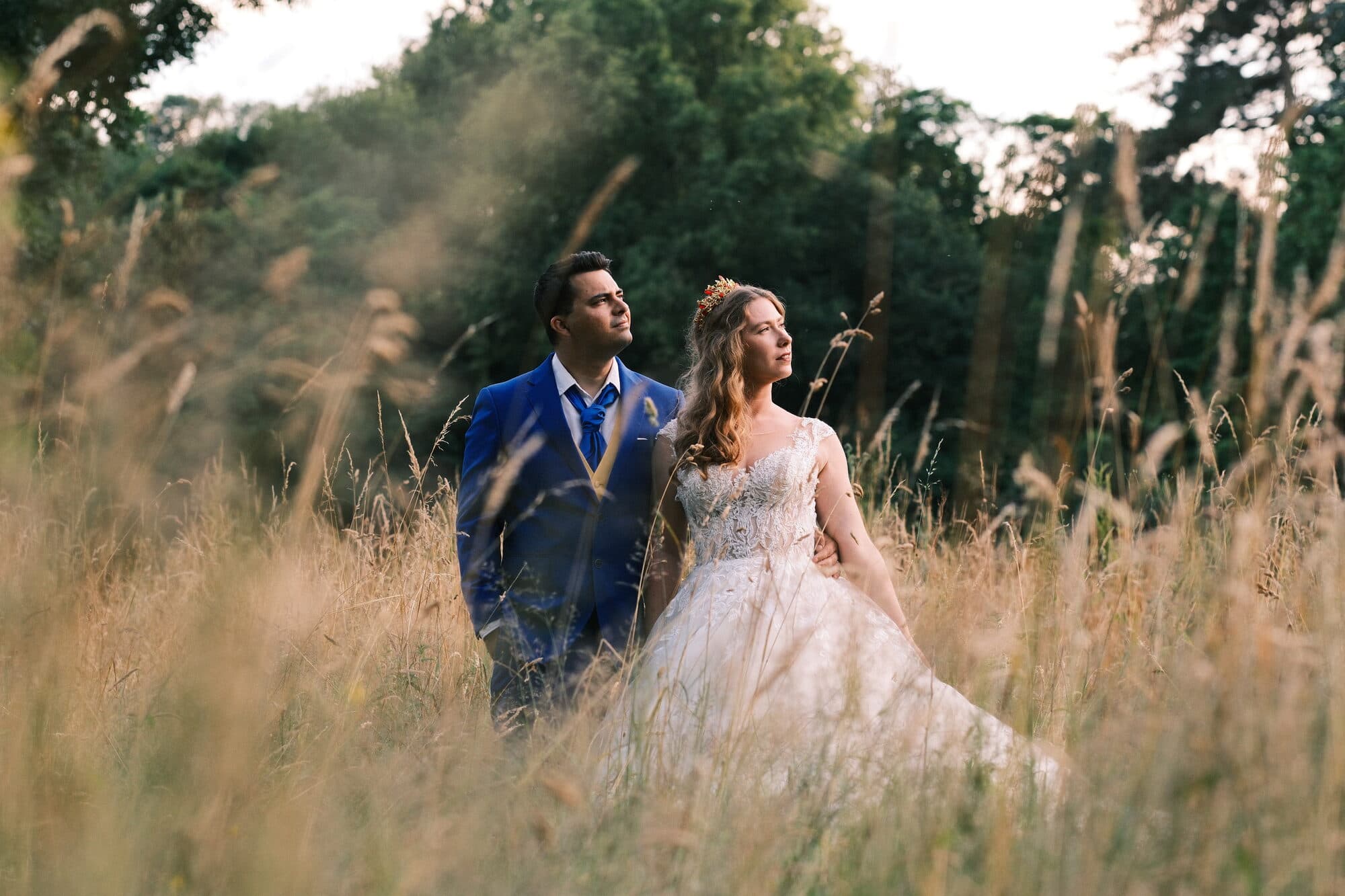 Mariage — les mariés, complices, marchant dans un champ en lumière dorée